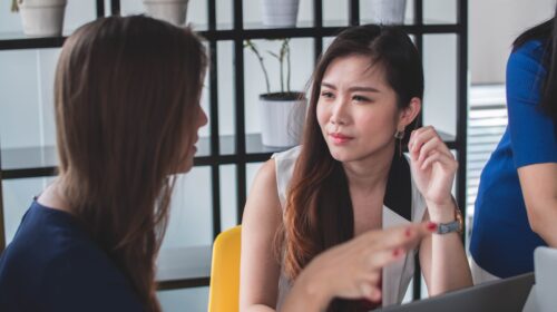 woman sitting on yellow armless chair near gray laptop computer