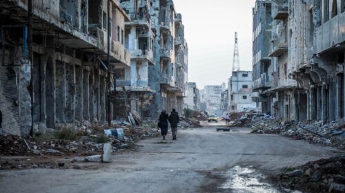 a couple of people walking down a dirty street