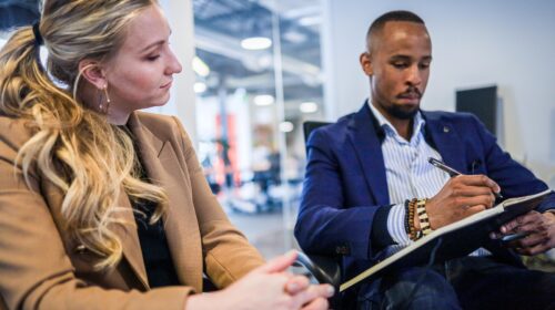 man in black suit jacket holding black smartphone